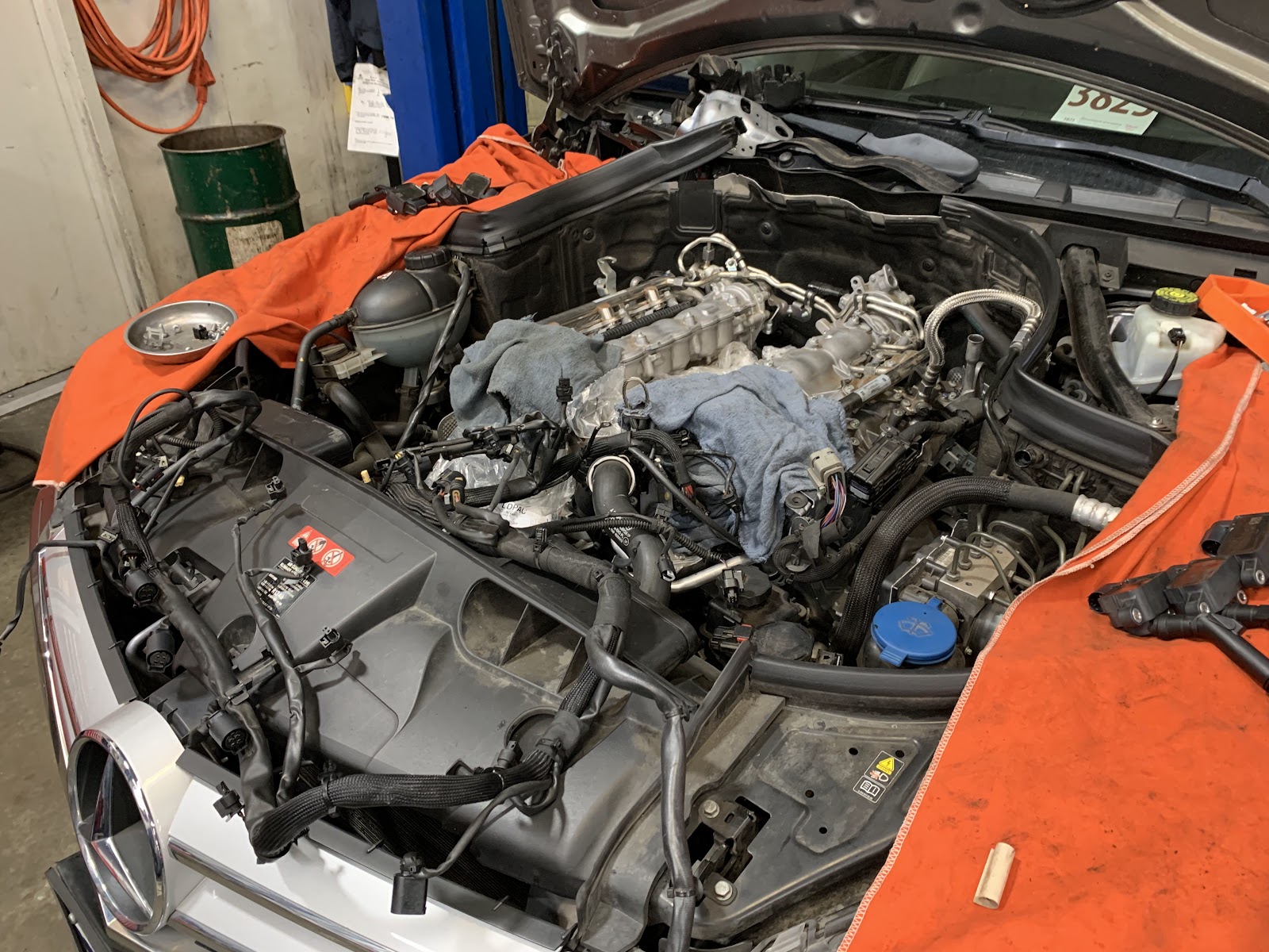 A Mercedes engine bay mid-repair, fender covers on